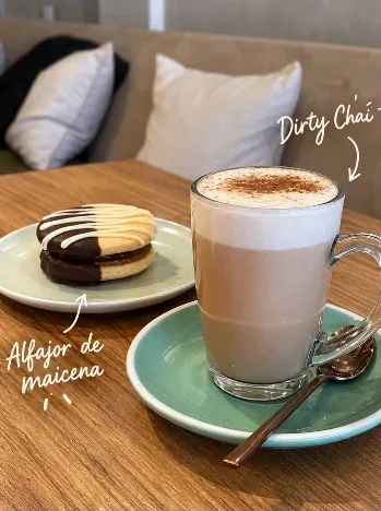 Dirty chai en vaso de vidrio junto a un alfajor de chocolate